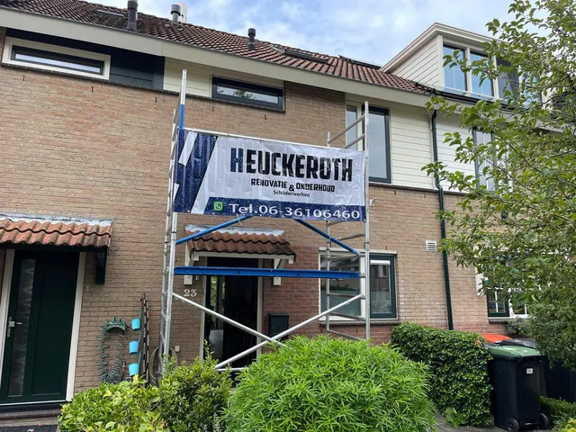 Schilder brengt verf aan op buitenkozijn van een woning